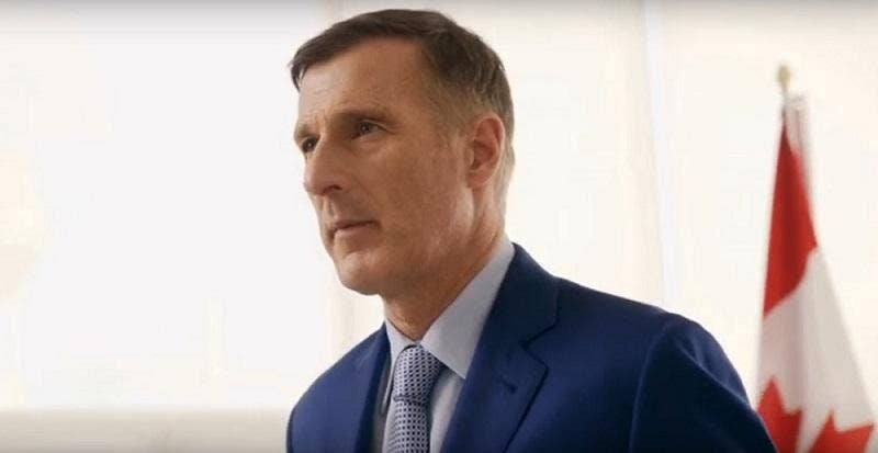 Image of Maxime Bernier in a blue suit with a glimpse of Canadian flag in the background