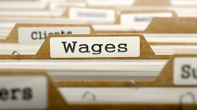 Image of files in a filing cabinet with tab labelled wages visible.