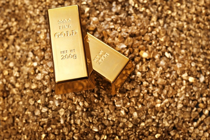 Gold bars sitting on a pile of gold dust
