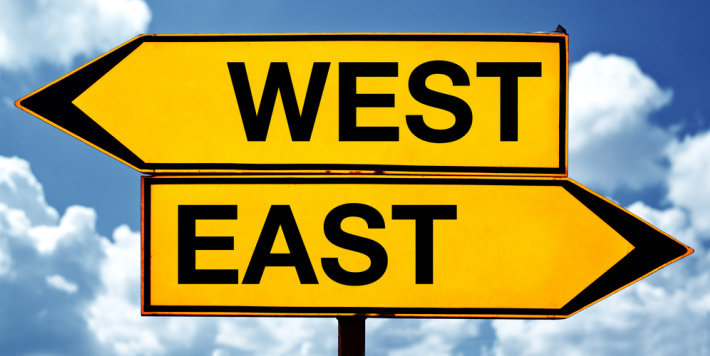 two street signs, one says east, one says west, pointing in opposite directions