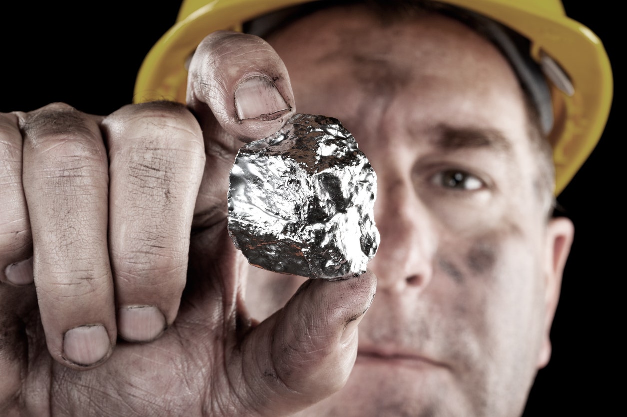 Image of a miner holding up a large gold nugget.