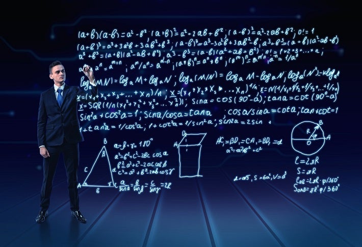 A man standing on the stage and explaining something from the big screen behind him