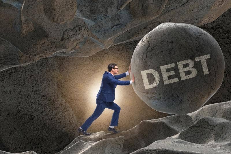 Image shows a man pushing big boulder with debt written on it